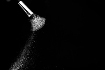 white powder splash and brush for makeup artist or beauty blogger in black background