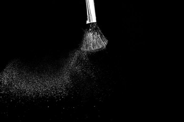 white powder splash and brush for makeup artist or beauty blogger in black background