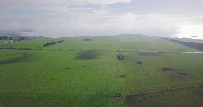 Amazing aerial flight over green field towards coastline in Tasmania, Australia