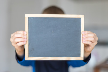 boy holding empty blackboard