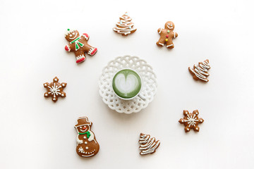 Fresh useful green matcha latte coffee in a beautiful mug on a white background. Nearby lay Christmas gingerbread.