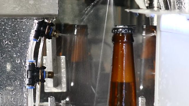 Brewery concept. Beer factory. Automatic Beer Bottling Line. Close up shot of final part of beer bottles production on transporting line. Ready bottles are being washed. 4k