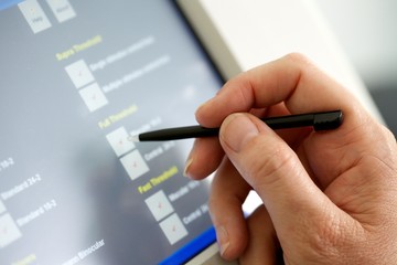 close up of a male white hand using a stylus pen on a touch screen key pad