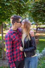 A man kisses a girl in the park. Man in plaid shirt. Couple in love