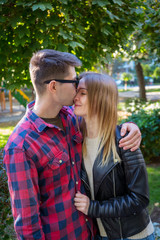 A man hugs a girl in the park. Man in plaid shirt. Couple in love