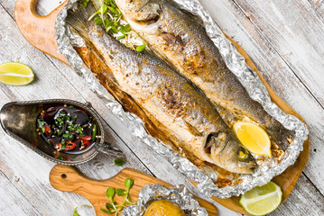 Fresh baked fish sea bass (Dicentrarchus labrax) on a light wooden background