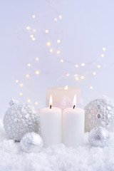 Obraz na płótnie Canvas Christmas candles on the snow and Christmas lights. Festive Christmas background