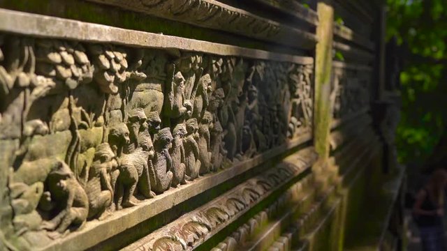 Slowmotion Steadicam shot of the walls and statues of the temple inside of a Monkeys forest covered with stone carving