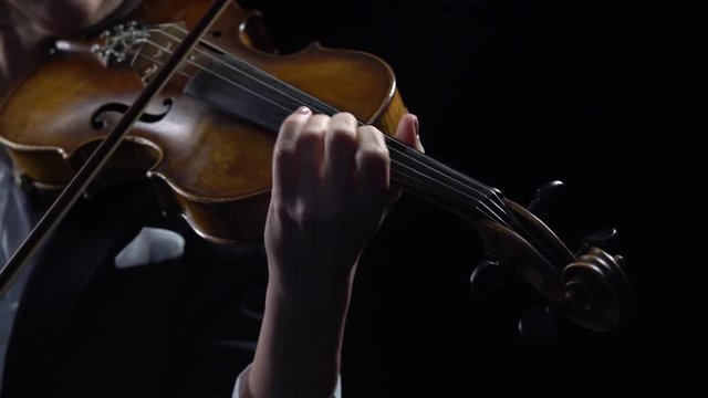 Violinist holds a bow and plays . Black background. Close up