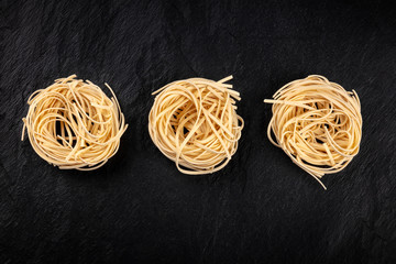 A photo of three nests of udon noodles, shot from the top on a black background with a place for text