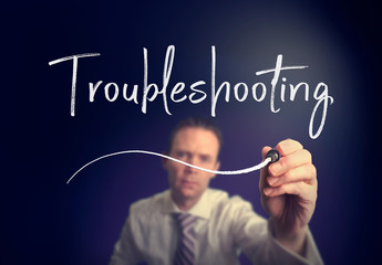 A businessman writing a Troubleshooting concept with a white pen on a clear screen.