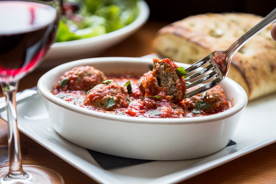 Fork Dipping into Braised Meatballs in Marinara Sauce
