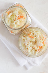 Top view two glass jars with sauerkraut on white napkin on white background.