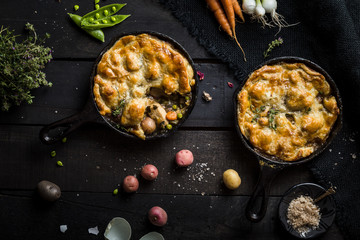 Pair of Chicken Pot Pies Baked in Cast Iron Skillets on Dark Background