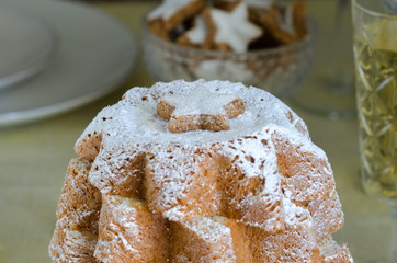 Close up of Pandoro, Italian Christmas cake with christmas decoration and champagne on festive table. Beautiful Xmas food concept.