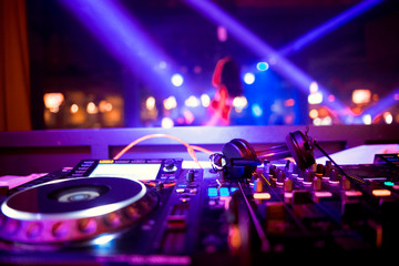 Fototapeta na wymiar In selective focus of Pro dj controller.The DJ console deejay mixing desk at music party in nightclub with colored disco lights. Close up view