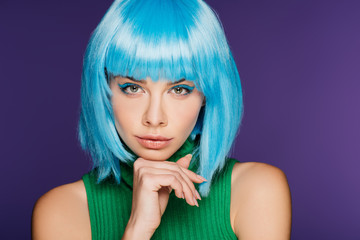 Fototapeta premium pensive stylish girl posing in blue wig, isolated on purple