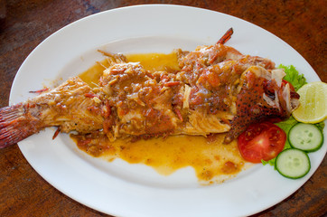 on a white plate fish on a grill with vegetables
