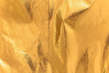 Highly detailed texture of a rusty golden yellow shimmering thermal blanket background.