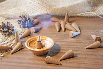 Cones Incense smoke in a ceramic stand on a wooden table. Aromatherapy theme background.