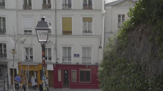 An artistic shot of a Parisian street lamp with a small gallery in the background and steps going down towards it
