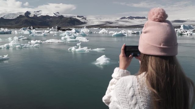 Iceland nature at Jokulsarlon Iceberg beach. Woman tourist taking photograph with mobile phone