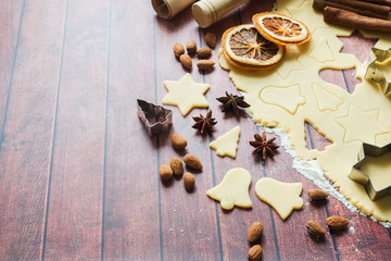 Ingredients for making Christmas cookies. Rolling pin cookie cutters cinnamon flour eggs butter dough on light background with copy space.