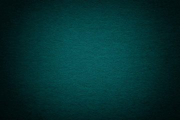 Texture of old dark turquoise paper background, closeup. Structure of dense deep bluish cardboard.