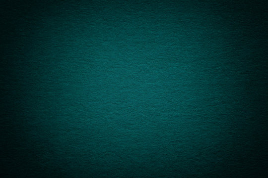 Texture of old dark turquoise paper background, closeup. Structure of dense deep bluish cardboard.