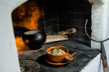 Ukrainian porridge in a clay bowl on the background of the oven