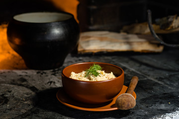 Ukrainian porridge in a clay bowl on the background of the oven