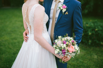 wedding couple hold bouquet with roses and camomiles