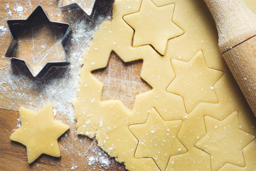 Ingredients for making Christmas cookies. Rolling pin cookie cutters cinnamon flour eggs butter dough on light background with copy space.