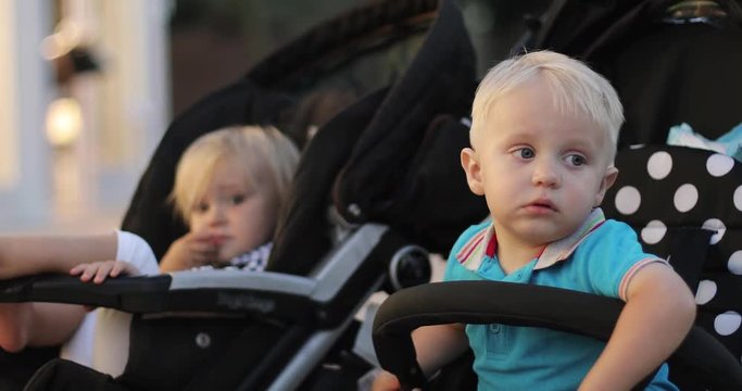 Sad children are sitting in baby strollers.