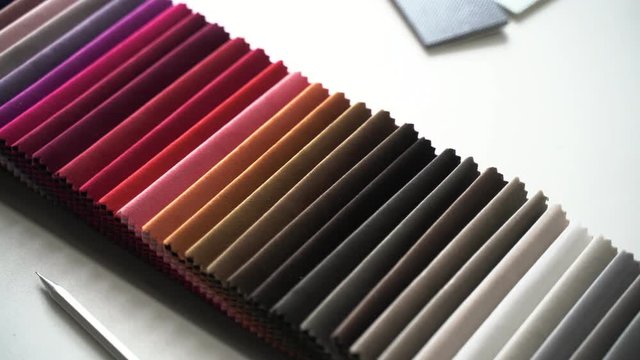 Interior designer selects fabric samples. Designer at work. Architect desk. Decoration. Decorative material. Flatlay. Woman holds her finger on the samples of designer textiles