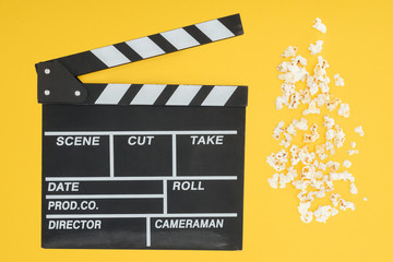 top view of clapperboard and fresh crunchy popcorn isolated on yellow