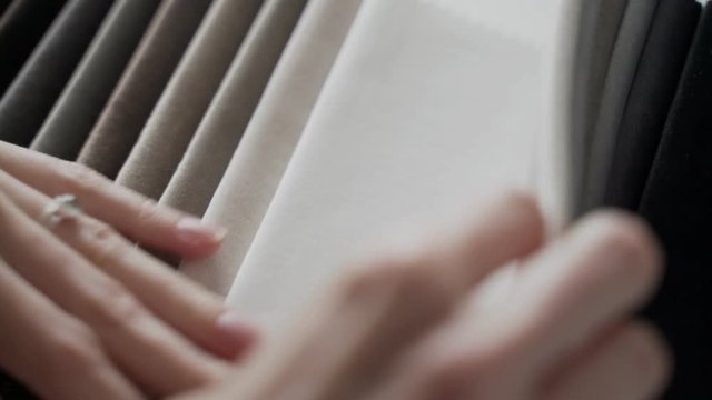 Interior designer selects fabric samples. Designer at work. Architect desk. Decoration. Decorative material. Flatlay. Woman chooses the color of designer velvet in shades of grey.