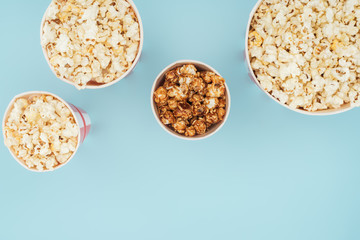 top view of striped buckets with fresh popcorn isolated on blue
