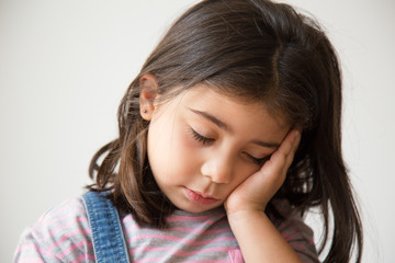Tired Latin kid with closed eyes sleeping on hand. Exhausted Hispanic little girl. Isolated on...