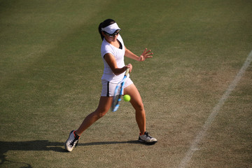 天然芝のコートでフォアハンドストロークを打つジュニアテニスプレイヤー