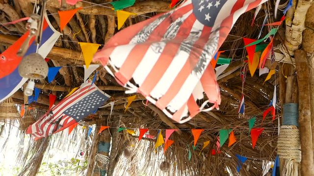 Decorative national flags of different countries hanging on strings in wooden tropical bungalow. Exotic rasta bar interior. Summer beach house on Koh Phangan island, Thailand.
