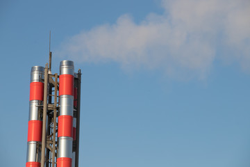 Industrial pipe against a bright sky in a clear sunny day. The boiler house in none-active mode, there is a small smoke from pipe.