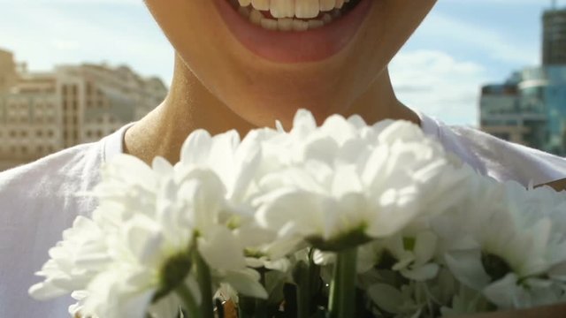 Pretty afro-american woman sniffing white flowers aroma and smiling, close up