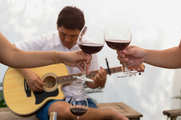 Friends celebrating and playing guitar while drinking red wine.