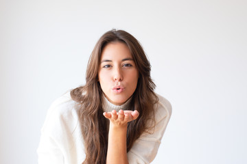 Pretty cheerful Hispanic girl blowing kiss from hand. Stylish young woman. Isolated on white. Love...