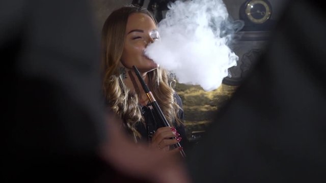Hookah smoker. Young woman smoking shisha or hookah in cafe or bar. Resting in shishabar lounge.