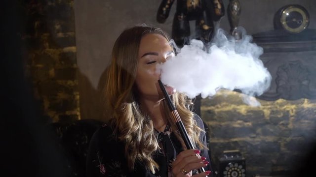 Hookah smoker. Young woman smoking shisha or hookah in cafe or bar. Resting in shishabar lounge.
