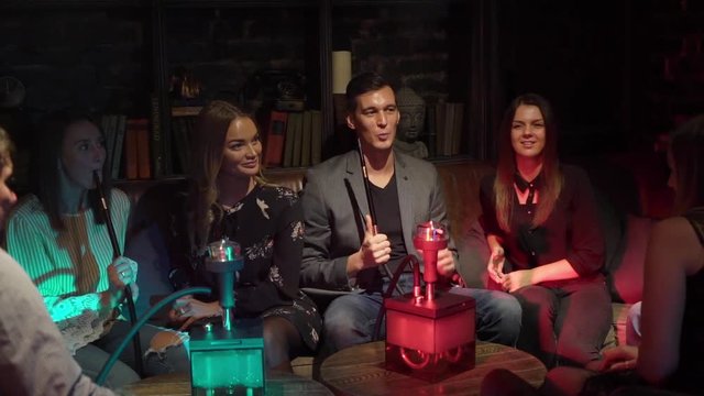 Hookah smoker. Group of young man, woman and couples smoking shisha or hookah in cafe or bar. Resting in shishabar lounge.