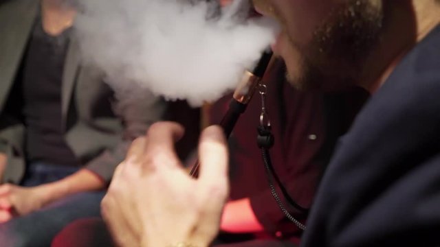 Hookah smoker. Group of young man, woman and couples smoking shisha or hookah in cafe or bar. Resting in shishabar lounge.