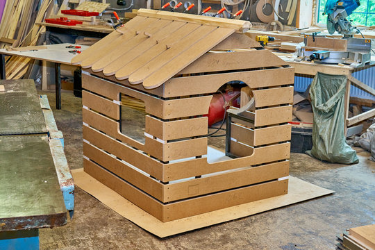 Children's play house in workshop. Woodworking and carpentry production. Clamping the roof ridge